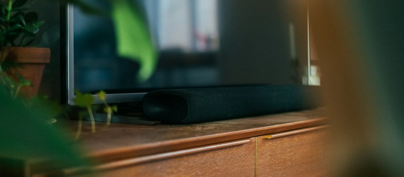 Ta filmkvällarna till en ny nivå med en soundbar Närbild på en elegant, mörk soundbar på ett trämöbel.
