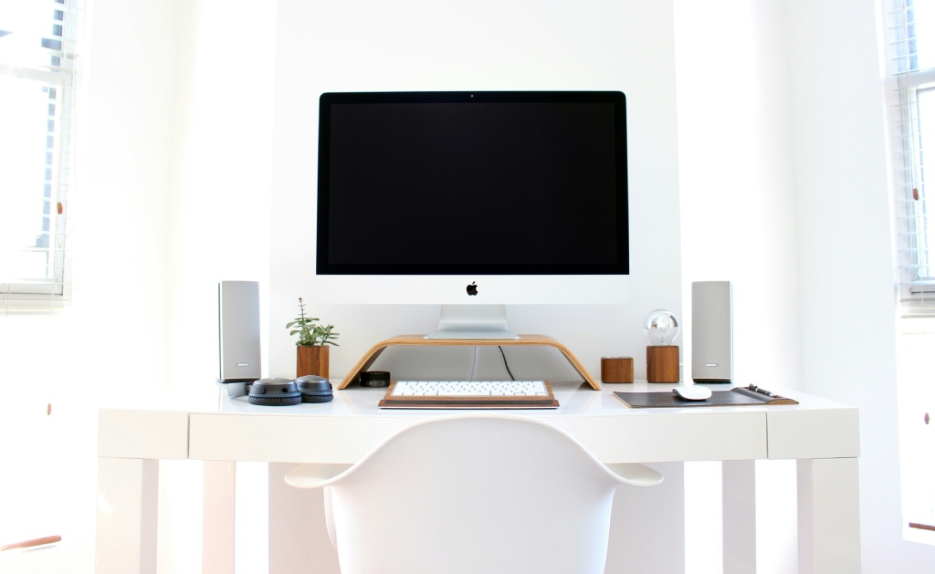 Minimalistiskt skrivbord med vita högtalare En modern vit interiör med ett skrivbord med en dator och två högtalare på vardera sidan