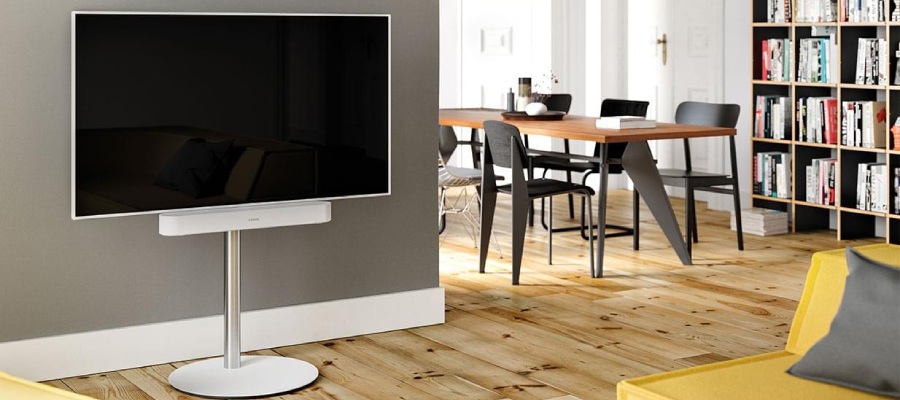 Vit TV på ett vitt stativ med en vit soundbar i vardagsrummet.